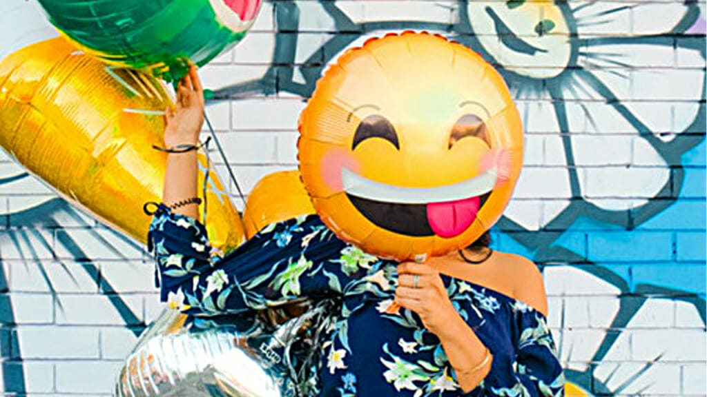 Was passiert im Körper, wenn wir lachen? (Junge mit mit vor dem Gesicht gehaltenen Smiley-Luftballon