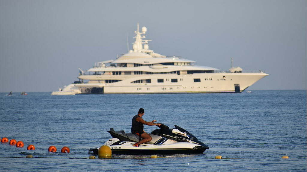 Mann mit kleinem Boot beobachtet große Yacht